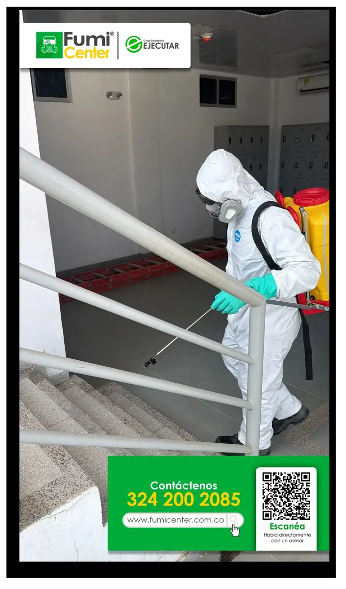 Técnico de FumiCenter con equipo de aplicación en una escalera interior de un edificio