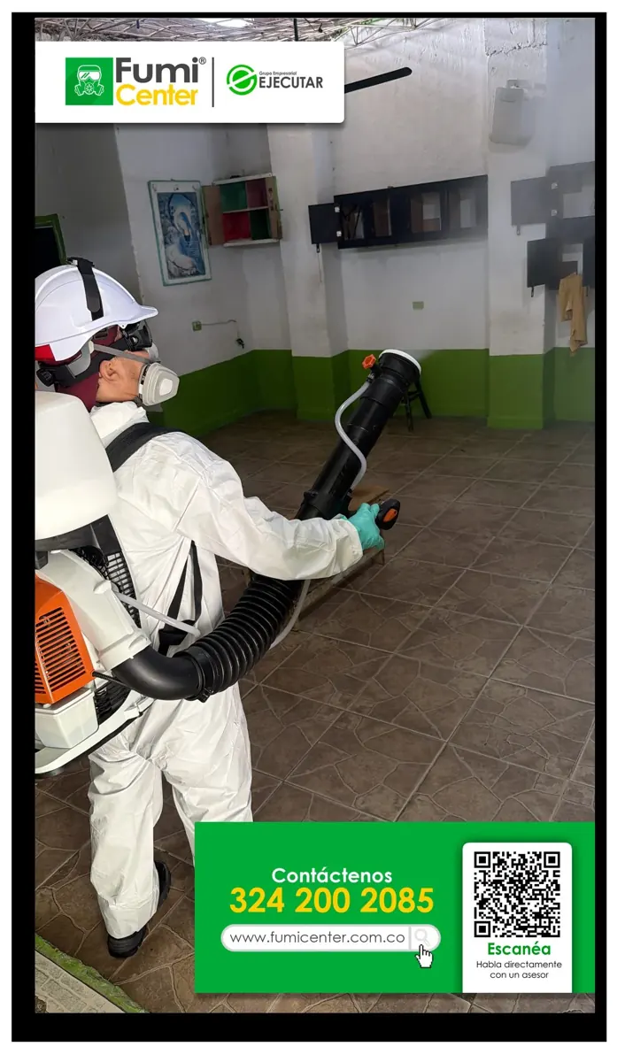 Técnico de FumiCenter con traje de protección, casco y equipo de aplicación en el interior de una edificación